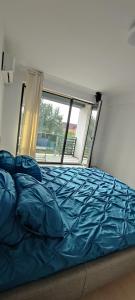 een bed met blauwe lakens in een kamer met een raam bij Infinit relax in Târgu Jiu