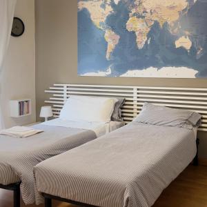 2 camas en un dormitorio con un mapa en la pared en Le stanze di Adele, en LʼAquila