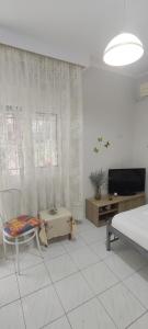 a living room with a bed and a tv and a chair at ANASTASIA studio in Kavala