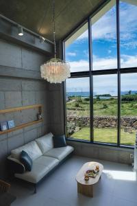 a living room with a couch and a table and windows at Dalthor Pension in Jeju