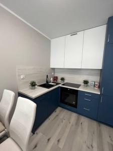 a kitchen with blue and white cabinets and white chairs at New Apartment - near Sky Tower - 7 People - New Building - Parking Place in Wrocław