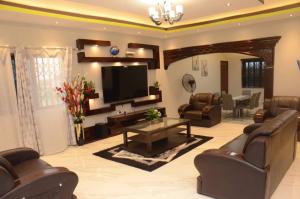 a living room with leather furniture and a flat screen tv at Zegio Villa in Jomo