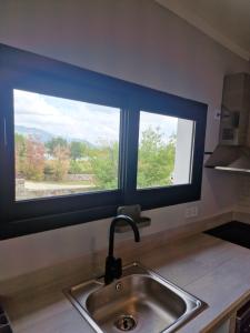 una cucina con due finestre sopra un lavandino di EL NIDO DEL AGUILA a Becerril de la Sierra
