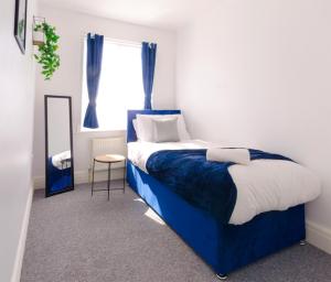 Un dormitorio con una cama azul y blanca y un espejo en Vibrant 4 Bedroom House With Game Area & Garden en Southampton