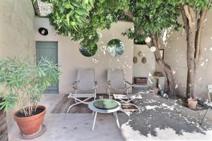 two chairs and a table in a courtyard with trees at La Maison de Cerise in Fourques