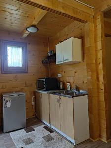 a kitchen in a log cabin with a sink and a microwave at Apartmani Kajkut in Banja Luka