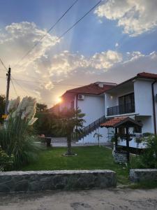 une maison au coucher du soleil derrière elle dans l'établissement Belov Rooms and Apartments, à Demir Kapiya