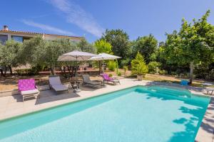 a pool with chairs and umbrellas next to a house at Gîte L'Escapade in Saint-Saturnin-dʼApt