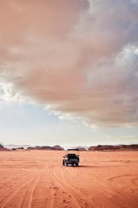 une voiture garée au milieu d'un désert dans l'établissement Art Camp Wadi Rum, à Wadi Rum