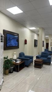 a waiting room with blue chairs and a table at فندق سرايا سيف مكة المحبس in Makkah