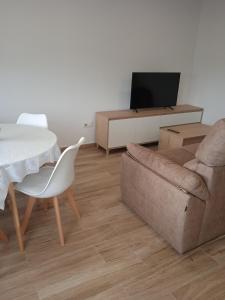 a living room with a table and a couch and a tv at Casa Begoña/la casa del timón in Muros