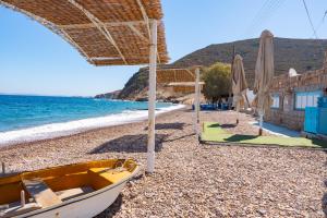 a boat on a rocky beach with an umbrella at Beachfront Lampis Dolphin 4 in Skala