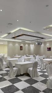 a room with white tables and chairs on a checkered floor at فندق سرايا سيف مكة المحبس in Makkah