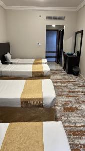 a hotel room with two beds and a desk at فندق سرايا سيف مكة المحبس in Makkah