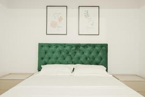 une chambre avec une tête de lit verte et trois gravures d'art encadrées dans l'établissement Himson-Green Apartment, à Iaşi