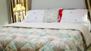 uma cama com lençóis e almofadas brancos e um candeeiro em Jeffston Court Apartments em Acra