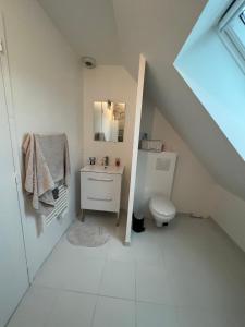 Baño blanco con lavabo y aseo en Chambre chez thomas, en Glos-sur-Lisieux