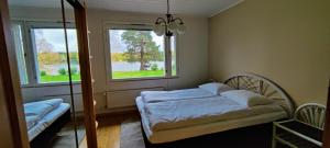 ein Schlafzimmer mit einem Bett und zwei Fenstern in der Unterkunft Riverside country house in Rovaniemi