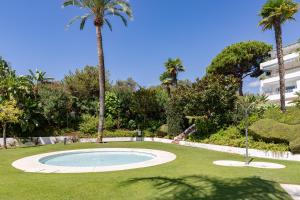 a pool in a yard with palm trees and a building at Casa Birdie By Kura Homes in Marbella