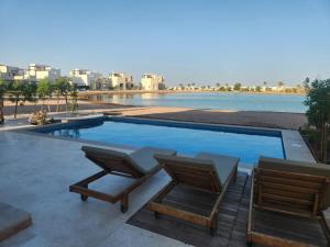 - une piscine avec 2 chaises à côté d'un corps d'eau dans l'établissement Luxury 4 bedroom villa - Cyan ElGouna, à Hurghada