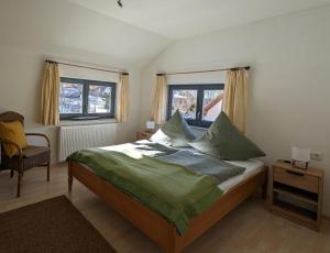 Schlafzimmer mit einem Bett, einem Stuhl und Fenstern in der Unterkunft Ferienhaus Ketterer Hinterzarten in Hinterzarten
