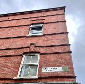 een bakstenen gebouw met twee ramen en een bord erop bij Grey Eagle Apartments Shoreditch in Londen