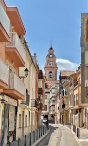 una calle de la ciudad con una torre del reloj en el fondo en Casa Lujosa con Sauna y Jacuzzi en la montaña., en Tavernes de Valldigna