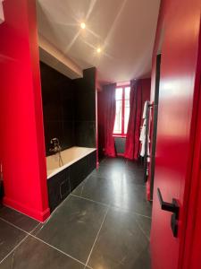 a red bathroom with a sink and a tub at La Maison à Pan De Bois Chambre Napoléon III in Vierzon
