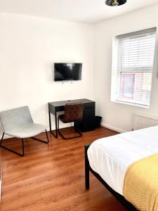 um quarto com uma cama, uma secretária e uma televisão em Grey Eagle Apartments Shoreditch em Londres