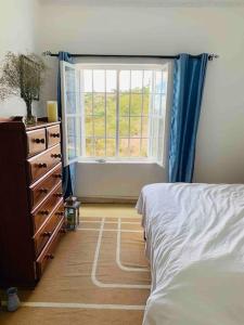 a bedroom with a bed and a dresser and a window at harmonious two bed cottage with breathtaking views in Kajiado