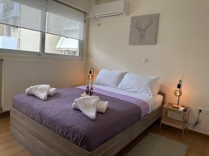 a bedroom with a bed with purple sheets and a window at LY Deluxe Apartment Athens in Athens