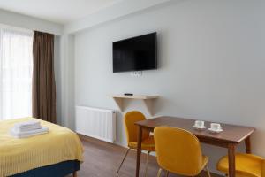 ein Hotelzimmer mit einem Tisch und Stühlen sowie einem TV in der Unterkunft Gudauri Ski Resort - Twins Mountain View Apartments in Gudauri