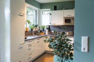 a kitchen with white cabinets and a potted plant at Familiensuite BoHo am See - Netflix - Grill - Parken in Möhnesee