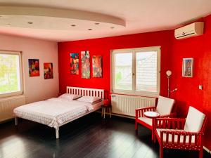 um quarto com paredes vermelhas e uma cama e duas cadeiras em Apartman STUDIO Sch Sch Sch em Saraievo