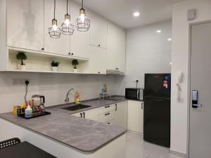uma cozinha com armários brancos e um frigorífico preto em Sky Trees at AEON Bukit Indah with Netflix and Wifi em Johor Bahru