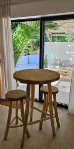 a wooden table and two stools in front of a window at Le Clos des Délices - Love Room in Aubagne