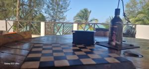 uma garrafa de vinho sentada num tabuleiro de xadrez sobre uma mesa em Ayla Beach House em Kiwengwa
