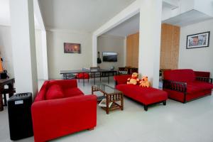 a living room with red chairs and a table at Hotel Vacanza in Mirissa