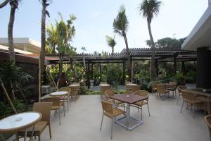 a patio with tables and chairs and palm trees at Ijen Suites Resort & Convention in Malang