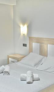 - 2 lits blancs dans une chambre avec des serviettes dans l'établissement Apartamento San Juan de la Cruz, à Gijón