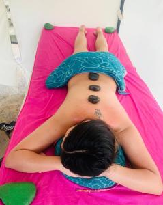 Una donna sdraiata su una coperta rosa con un tatuaggio sulla schiena di Finca Hotel Spa Zhay a Tibirita
