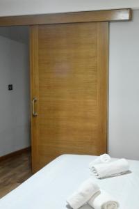 - un lit avec une porte en bois et 2 serviettes dans l'établissement Apartamento San Juan de la Cruz, à Gijón