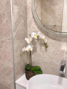 a bathroom with a sink and a mirror and white flowers at Nido dei Cigni in Turin