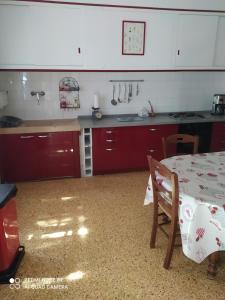 uma cozinha com armários vermelhos e uma mesa em La maison de Nazig em Pertuis