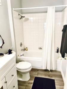 a white bathroom with a toilet and a bath tub at Gorgeous Serene Gated Newly Remodeled Townhouse in Las Vegas