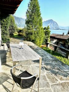 una mesa y sillas en un patio con vistas al agua en Ferienwohnung Il Sogno mit privatem Seeanstoss in Riva San Vitale-Lugano, en Riva San Vitale