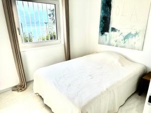 Habitación blanca con cama y ventana en Ferienwohnung Il Sogno mit privatem Seeanstoss in Riva San Vitale-Lugano, en Riva San Vitale