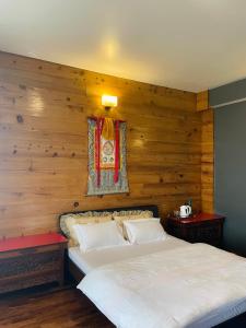 a bedroom with a wooden wall with two beds at Martam Farmhouse in Pelling