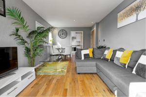 a living room with a gray couch and a tv at Sandy Lane Apartment in Skelmersdale