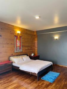 a bedroom with a bed with a wooden wall at Martam Farmhouse in Pelling